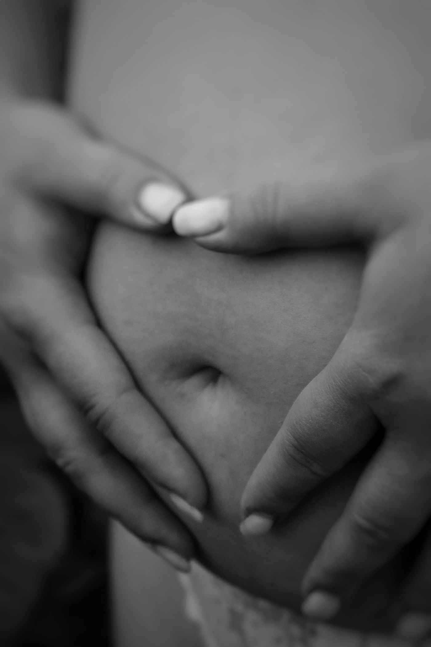 Two hands cradled together over a pregnant belly