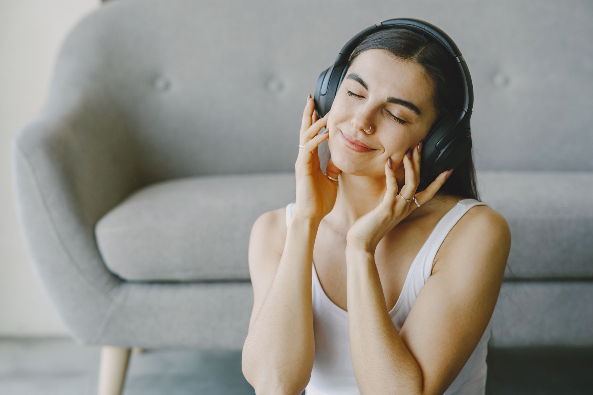 A woman relaxing with headphones on, eyes closed, listening